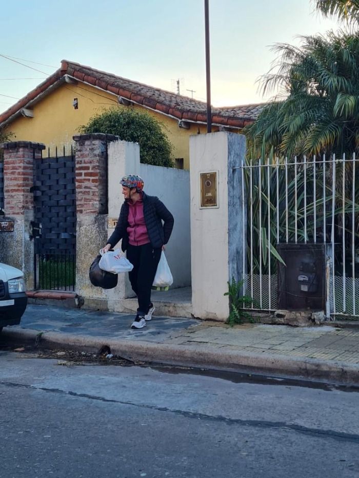Vieja loca saca la basura de su casa con un casco de ciclismo