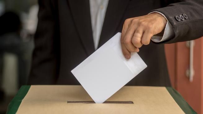 Un votante introduce papeletas de colores en una urna de Gran Canaria